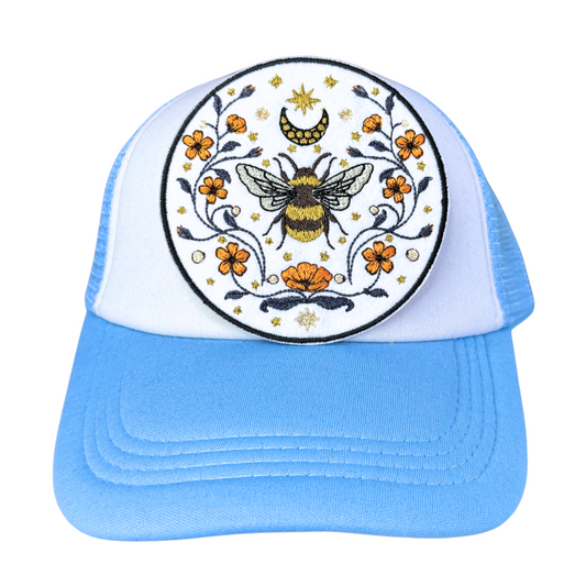 Celestial bee embroidered patch attached to a light blue and white trucker hat.
