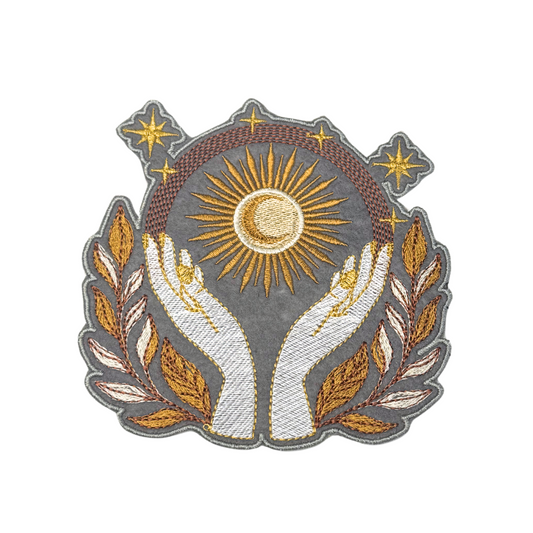 Celestial embroidered patch with hands holding golden sun and stars
