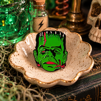 Classic green Frankenstein monster enamel pin in a moody vintage laboratory scene