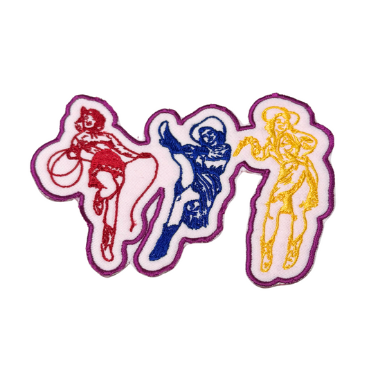 Embroidered patch with three colorful cowgirls in red, blue, and yellow outlined in pink
