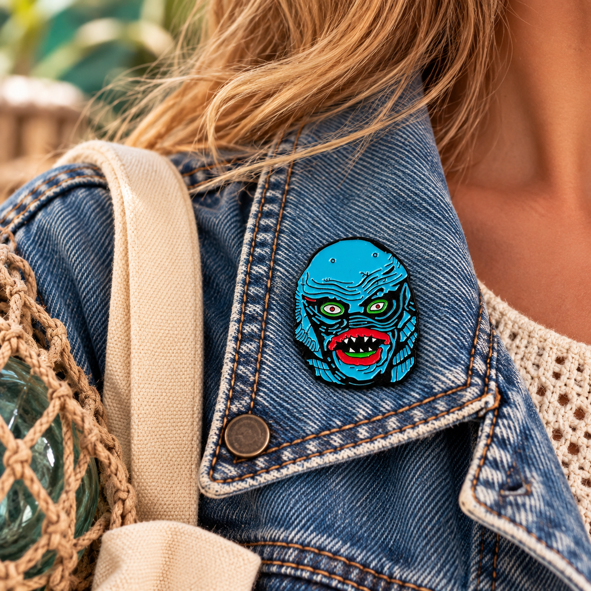 Blue retro lagoon creature enamel pin worn on a denim jacket