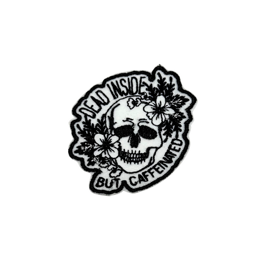 Black and white embroidered skull patch with floral details and “Dead Inside But Caffeinated” text
