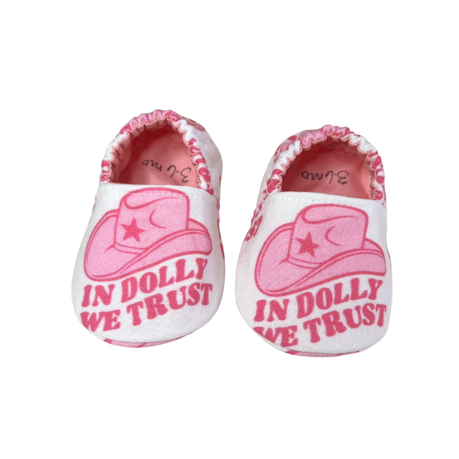 “Handmade soft sole baby shoes with pink cowboy hat and ‘In Dolly We Trust’ print, front view, 3-6 months”

