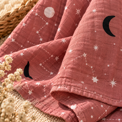 Close-up of dusty rose celestial cotton gauze swaddle fabric and finished edge