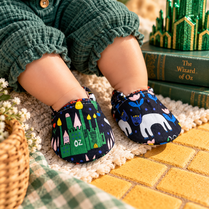 Emerald City wizard-inspired soft sole baby shoes worn by a baby in a whimsical green and gold storybook setting