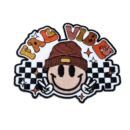 “Fall Vibes embroidered patch on white background with smiley face, beanie, retro lettering and checkerboard pattern”
