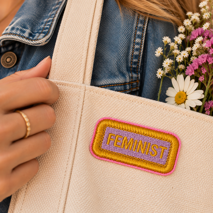 Small FEMINIST lavender and gold embroidered name tag patch on cream canvas tote with flowers