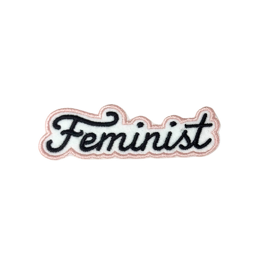 Feminist patch with black text and pink border on white background

