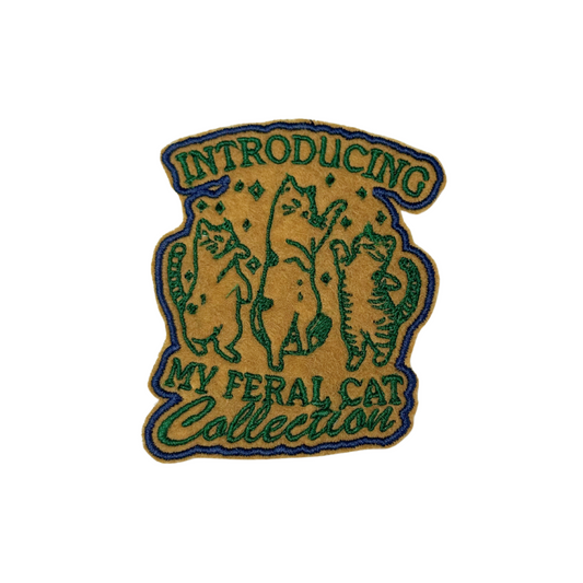 Front view of Introducing My Feral Cat Collection embroidered iron-on patch with green cats on mustard background
