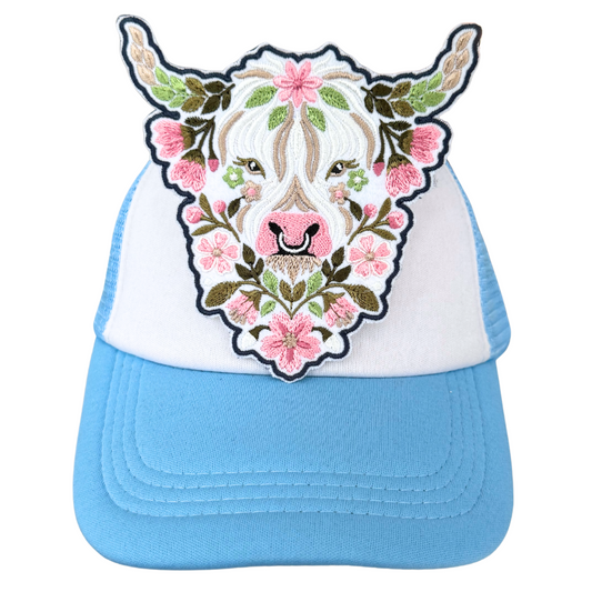 Floral Highland cow patch heat pressed onto blue and white trucker hat

