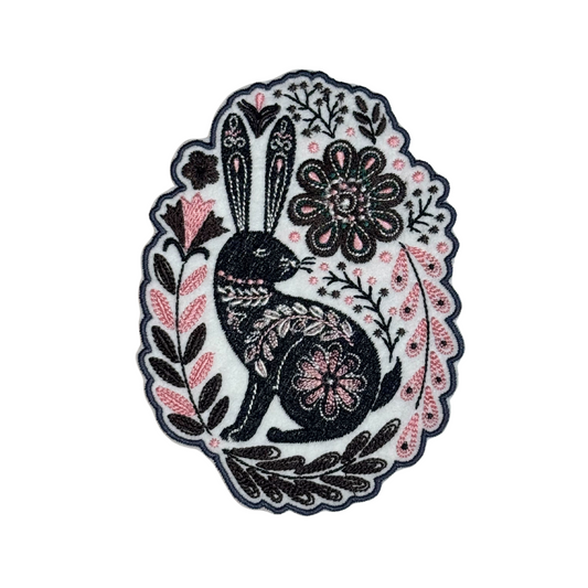 Embroidered folk art patch with black rabbit, pink flowers, and brown leaves
