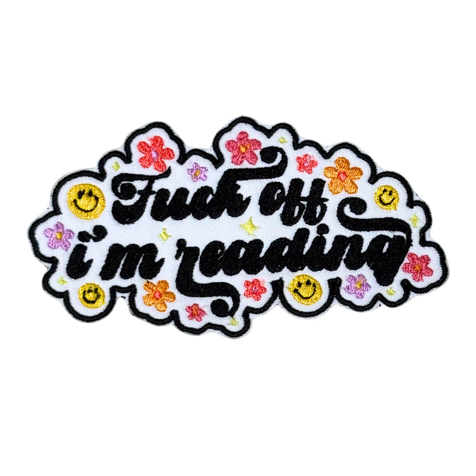 embroidered patch that says “fuck off, i’m reading” surrounded by smiley faces and flowers on white background
