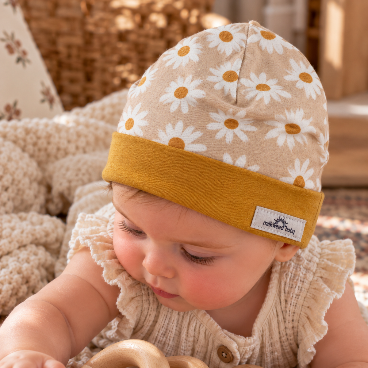 Baby wearing golden daisy organic cotton beanie