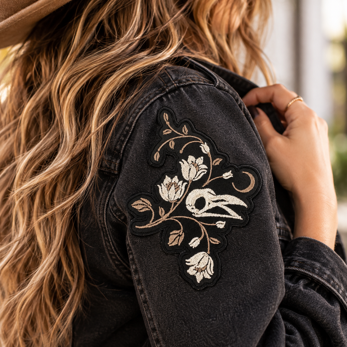 Gothic bird skull floral embroidered patch on a dark denim jacket