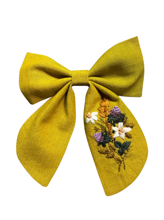 Yellow bow with floral embroidery on a white background