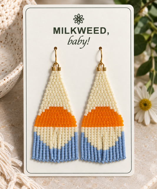 Hand-beaded ivory, orange and periwinkle fringe earrings on a Milkweed baby display card