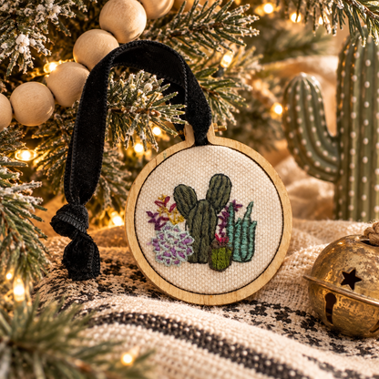 Hand-embroidered cactus Christmas ornament styled in a warm desert holiday scene
