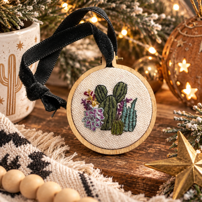 Hand-embroidered cactus and succulent Christmas ornament styled in a warm desert holiday scene