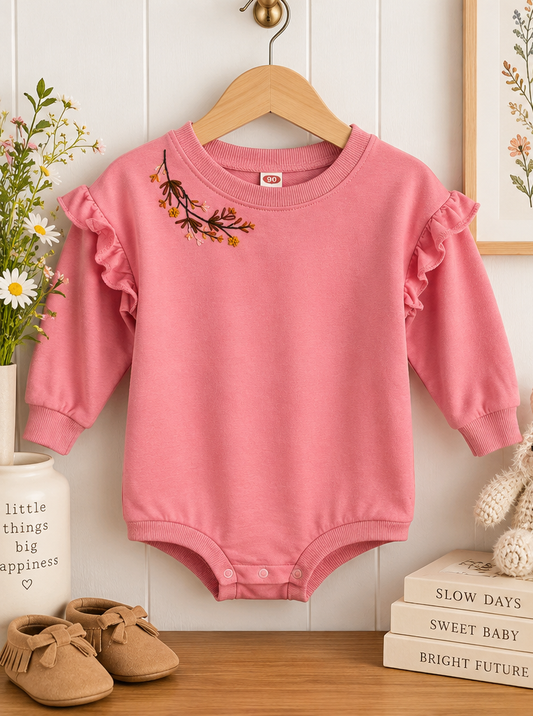 Hand-embroidered pink floral baby bodysuit styled product photo