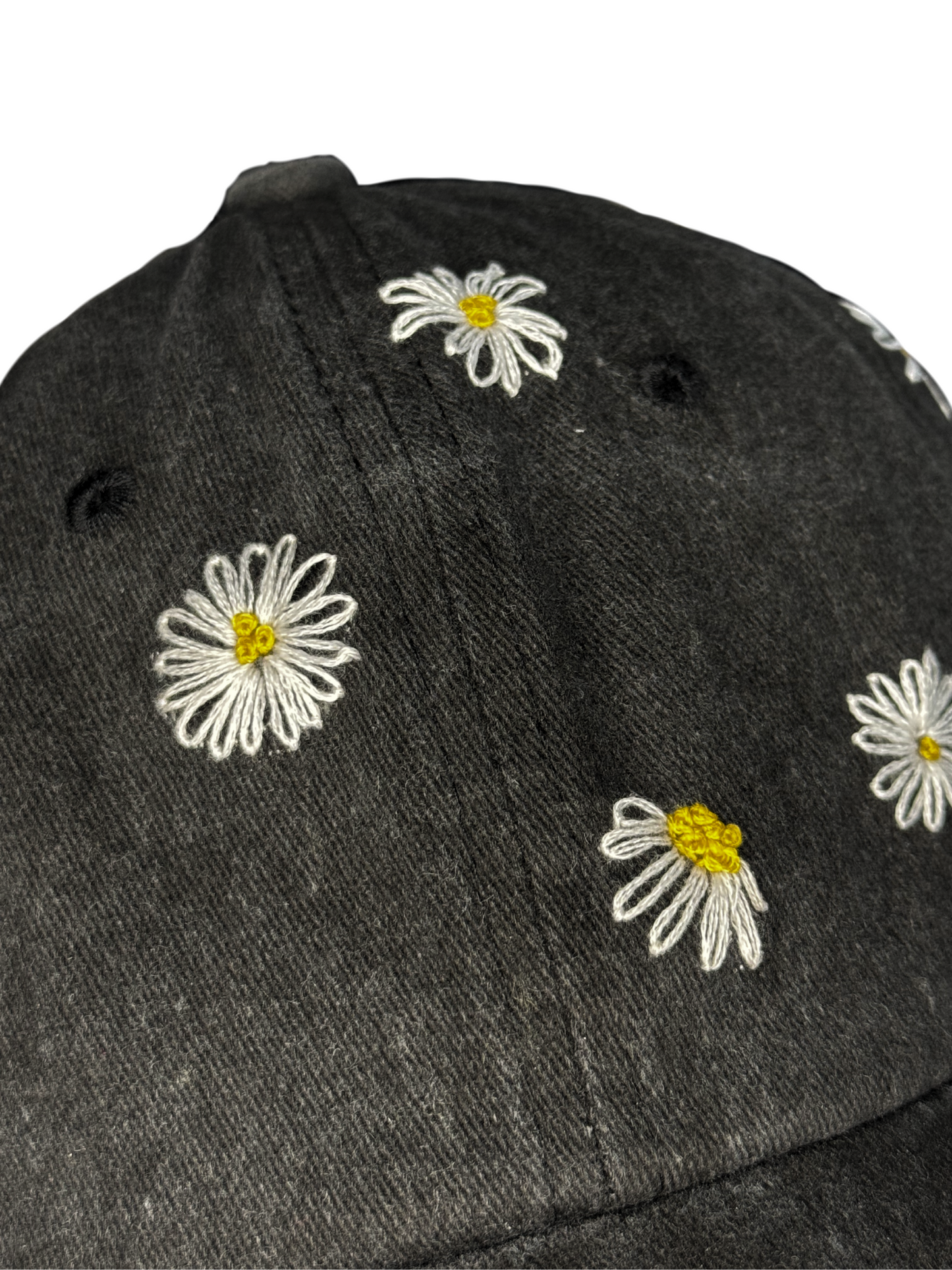 Black cap with white daisy flowers embroidered on a white background