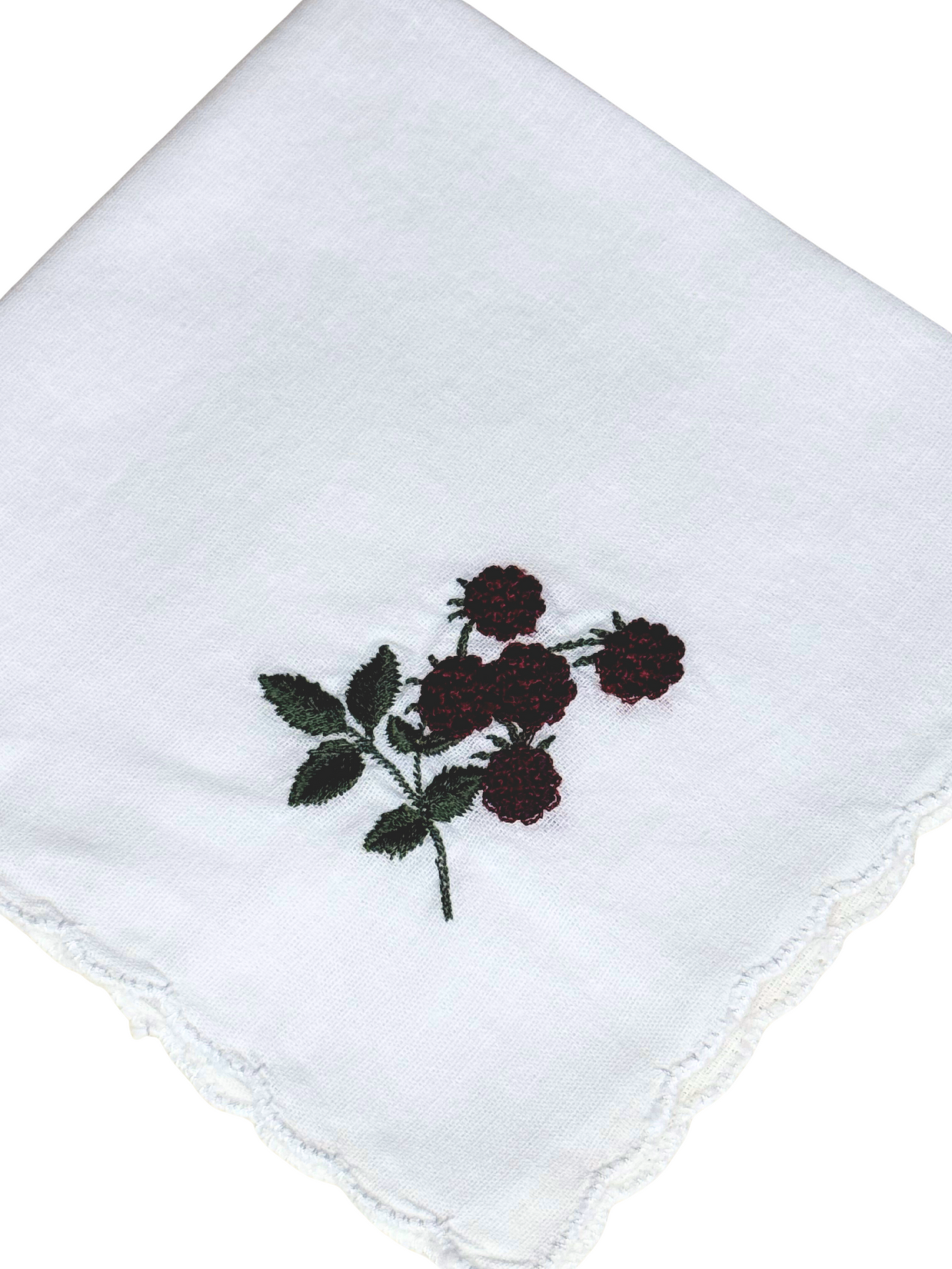 Close-up of blackberry embroidery with green leaves on scalloped white handkerchief

