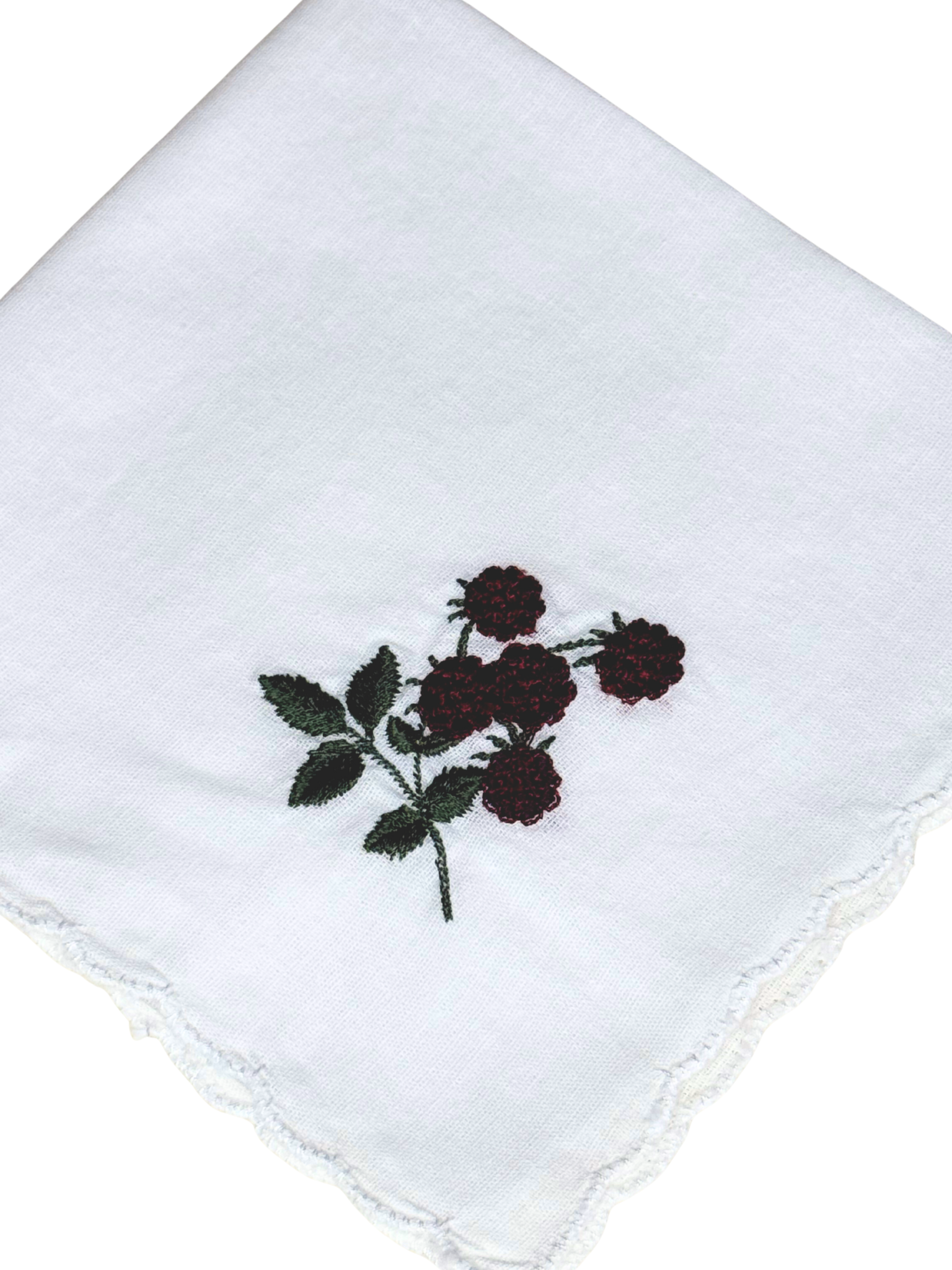 Close-up of blackberry embroidery with green leaves on scalloped white handkerchief

