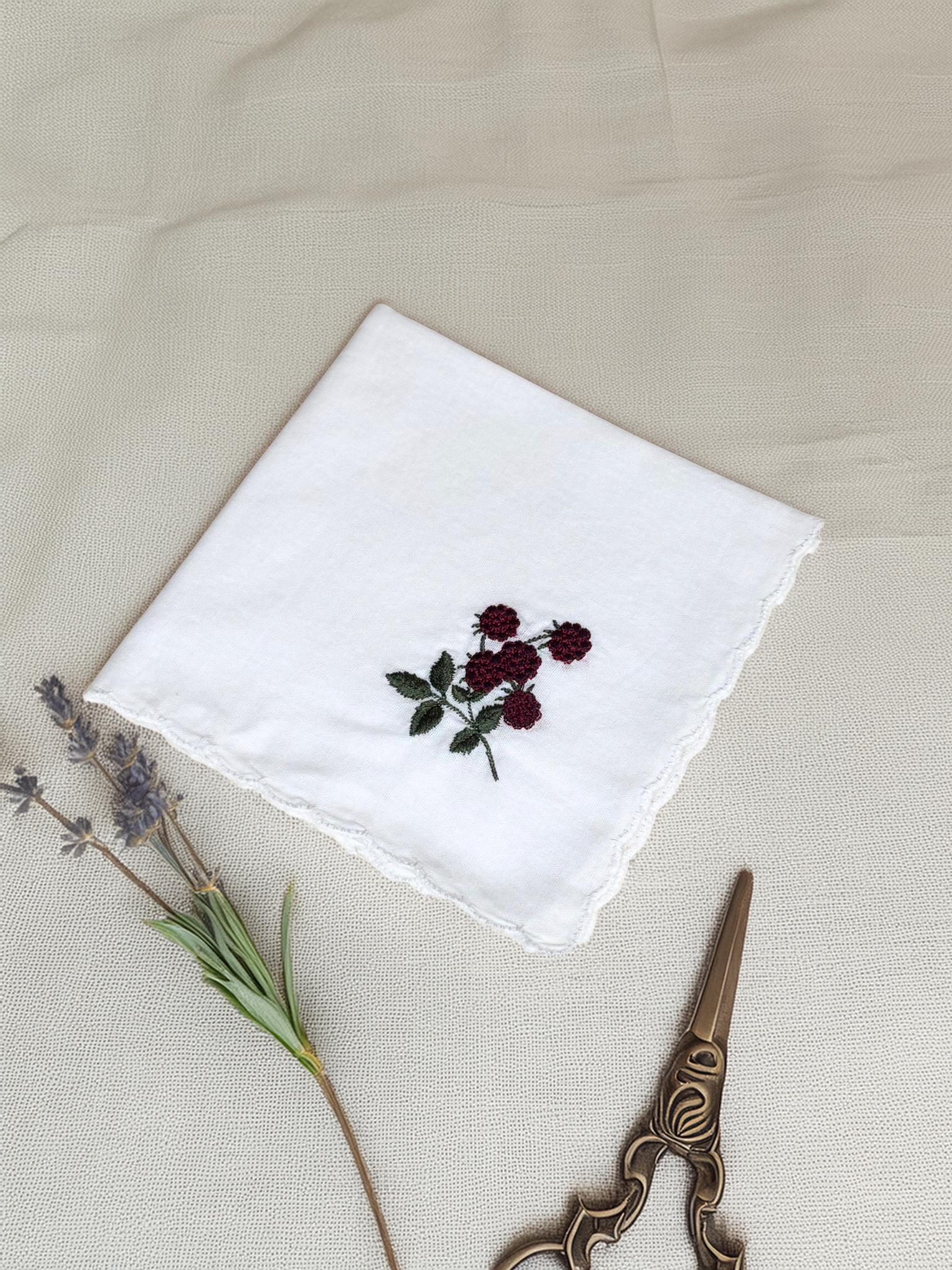 White embroidered handkerchief with blackberry design, styled with dried lavender and vintage scissors

