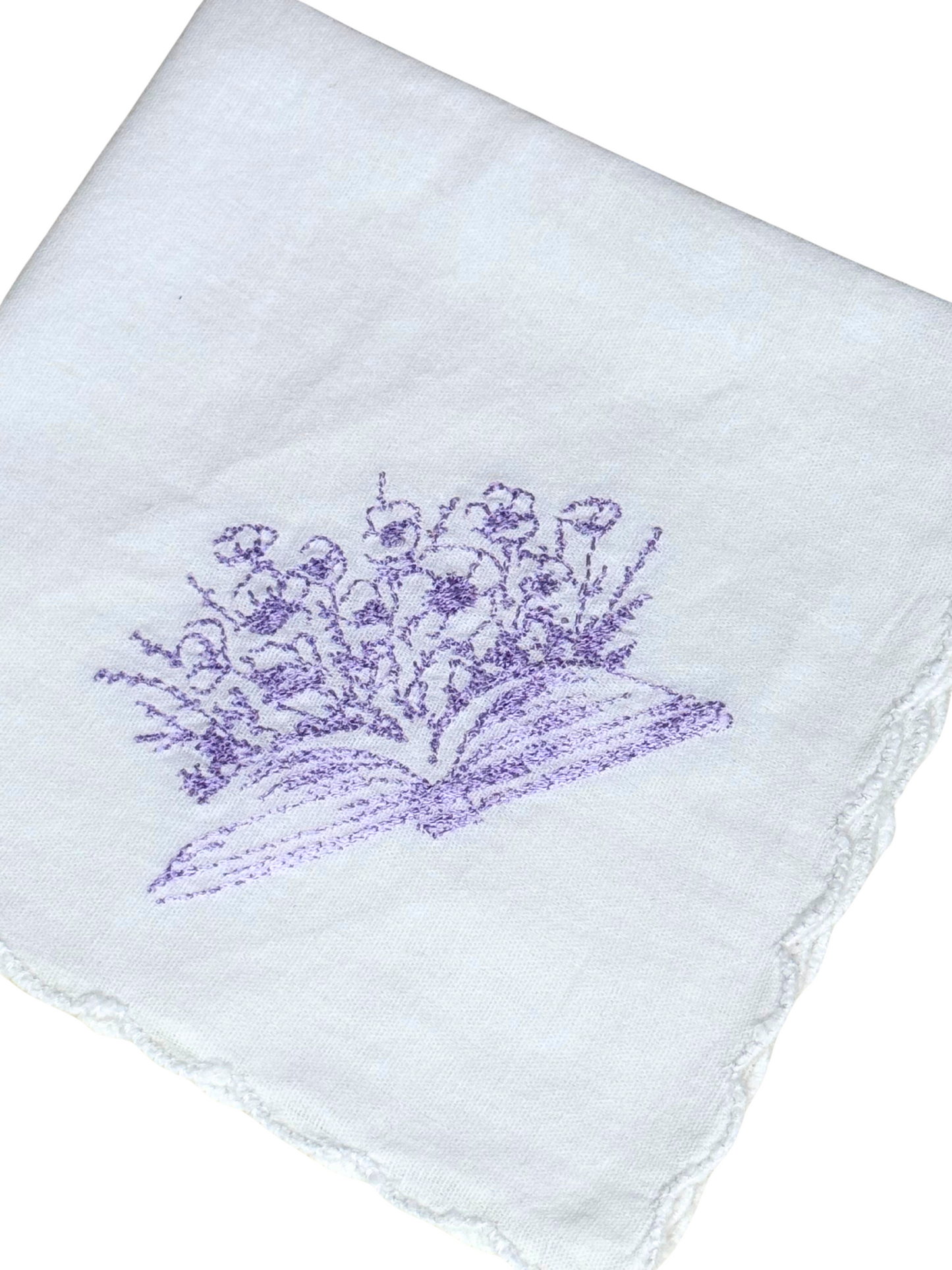 Close-up of lavender book and floral embroidery on handkerchief

