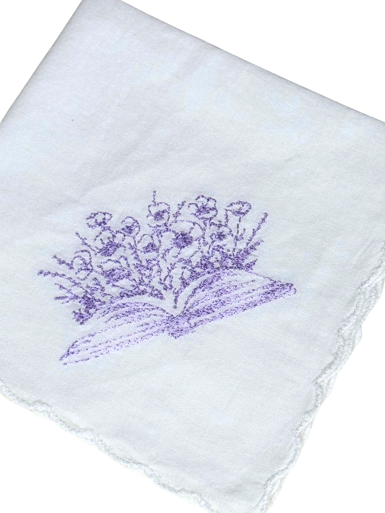 Close-up of lavender book and floral embroidery on handkerchief

