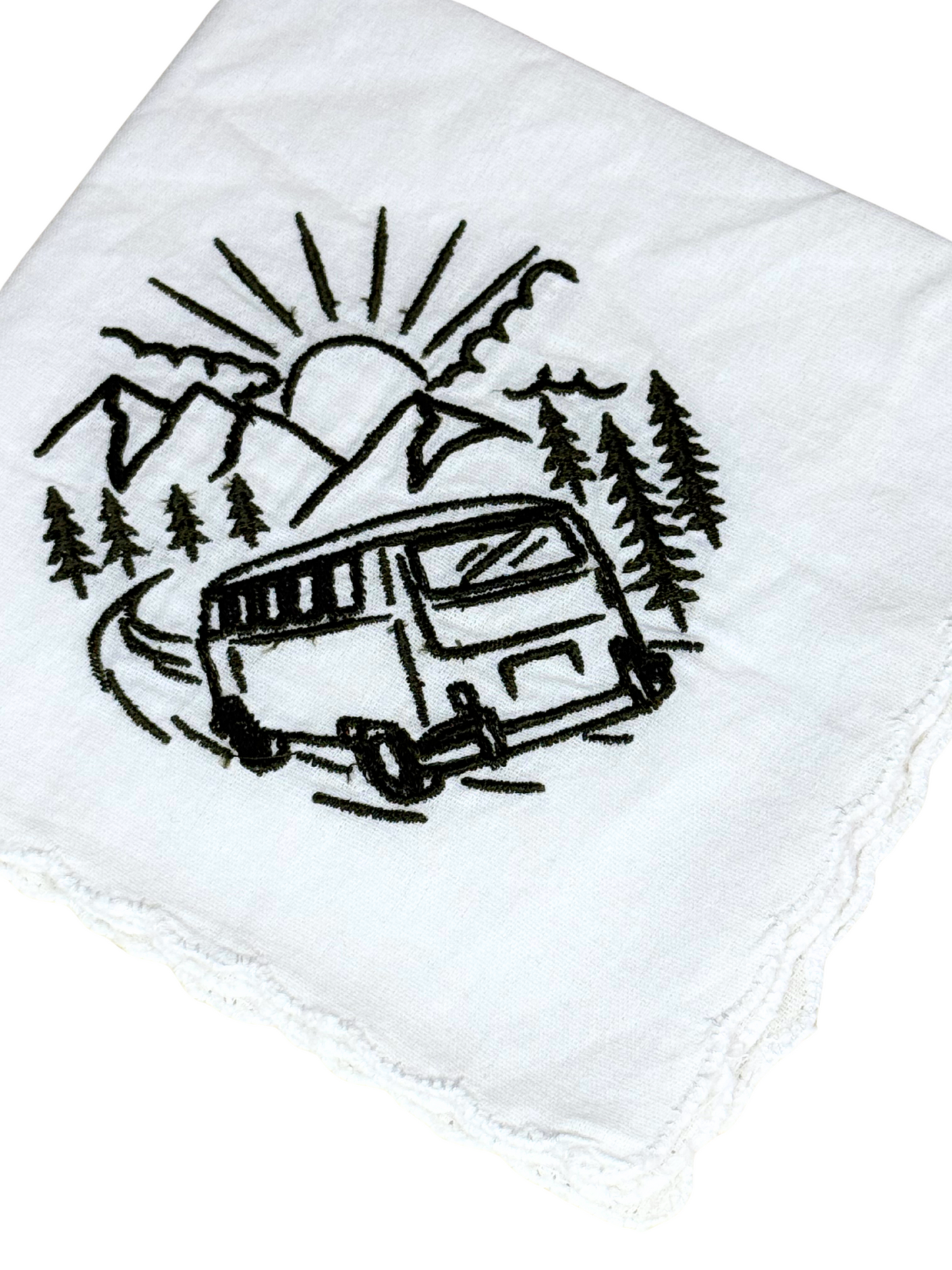 Close-up of embroidered camper van with sun, trees, and mountains in black thread