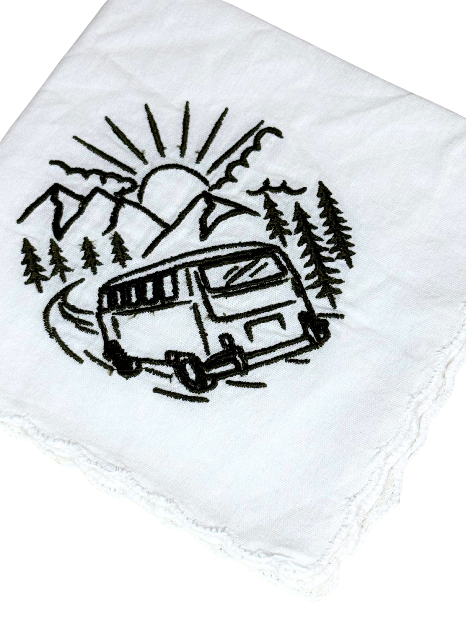 Close-up of embroidered camper van with sun, trees, and mountains in black thread