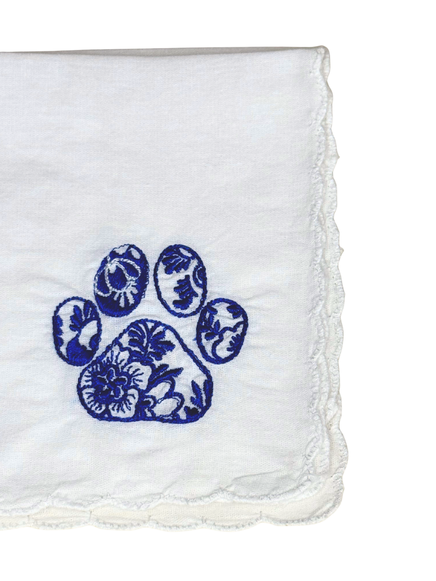 Close-up of embroidered blue dog paw with floral pattern on scalloped edge handkerchief

