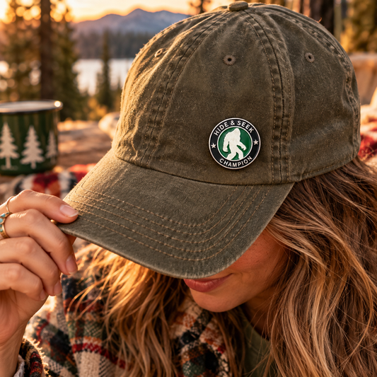 Hide and Seek Champion Bigfoot enamel pin on olive camp hat lifestyle image
