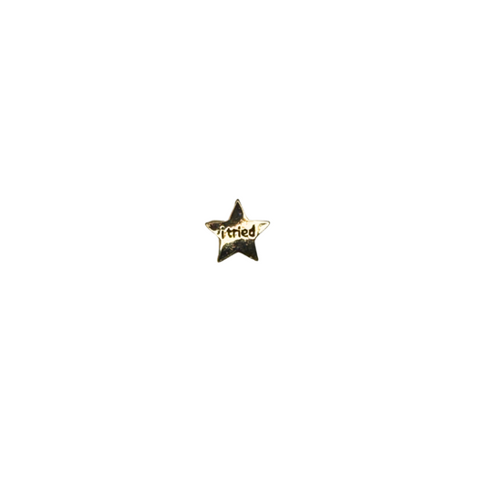 Hero shot of a gold star enamel pin that says “i tried”

