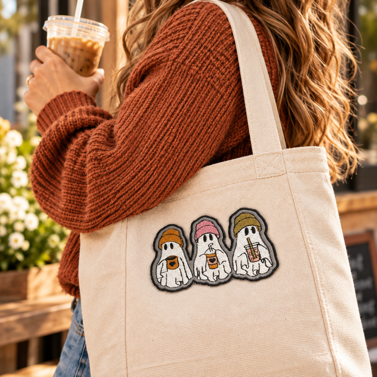 Ghost trio embroidered patch displayed on a cream canvas tote carried over the shoulder