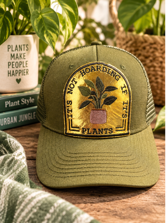 Olive green It's Not Hoarding If It's Plants trucker hat styled with houseplants