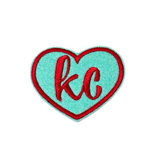 Aqua glitter heart patch with bold red “kc” embroidery and matching red border, inspired by Kansas City Current team colors

