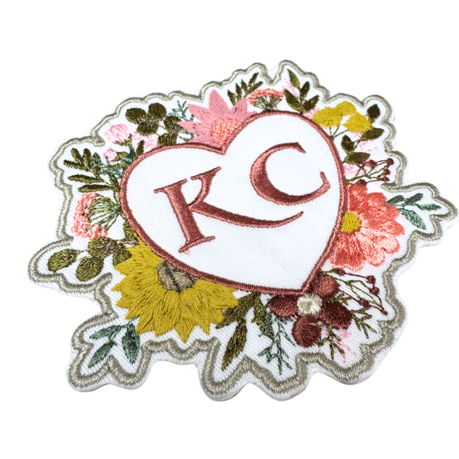 Angle view of embroidered floral heart KC patch showcasing intricate stitching.