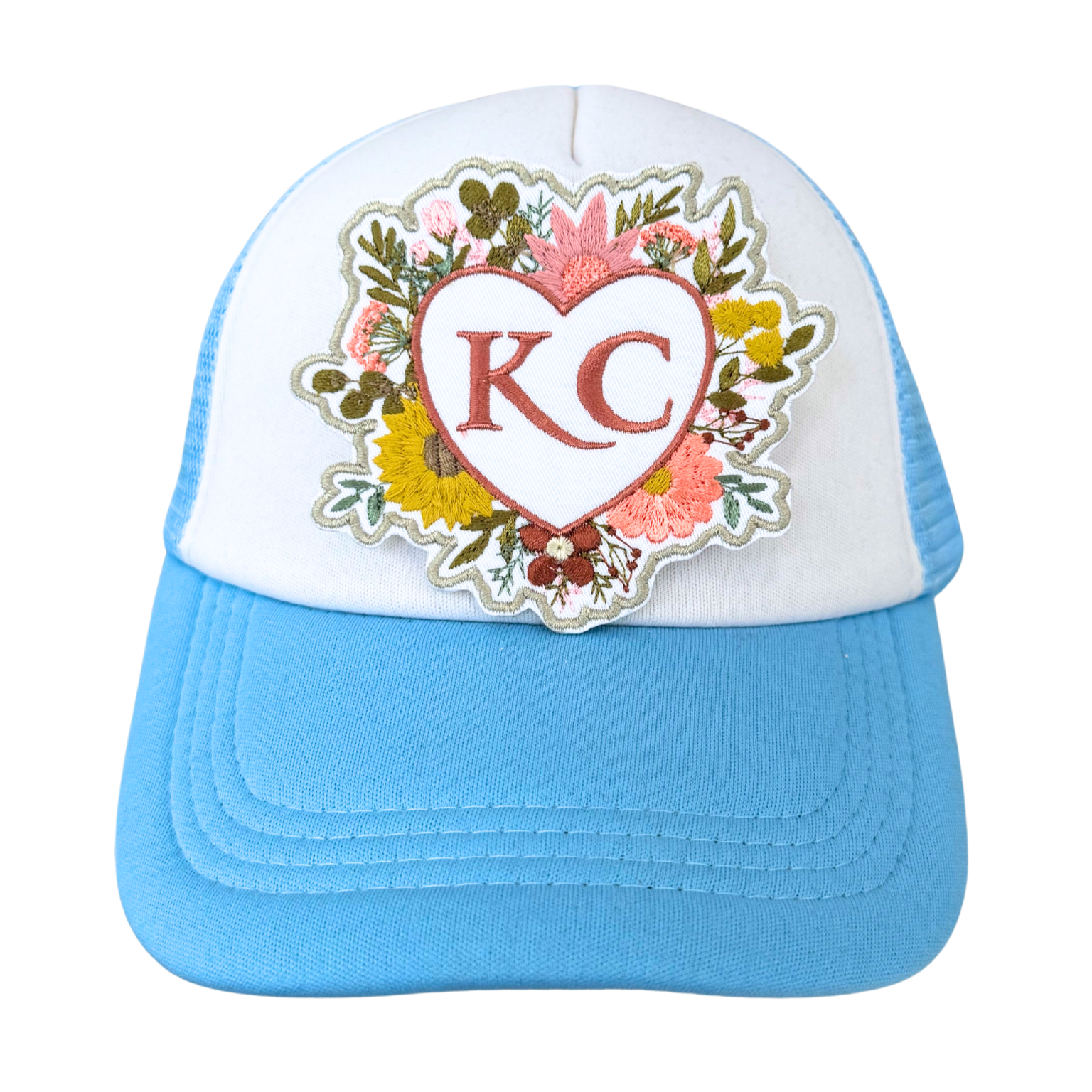 Blue trucker hat featuring embroidered floral heart KC patch.