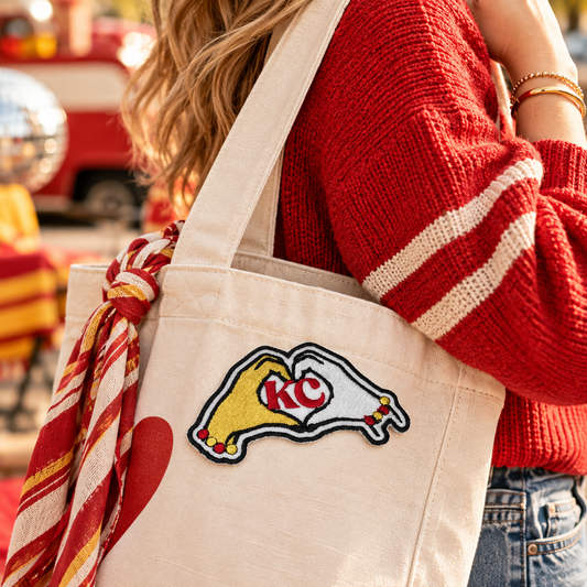KC heart hands embroidered patch on a cream canvas tote carried with a red sweater at a game-day gathering