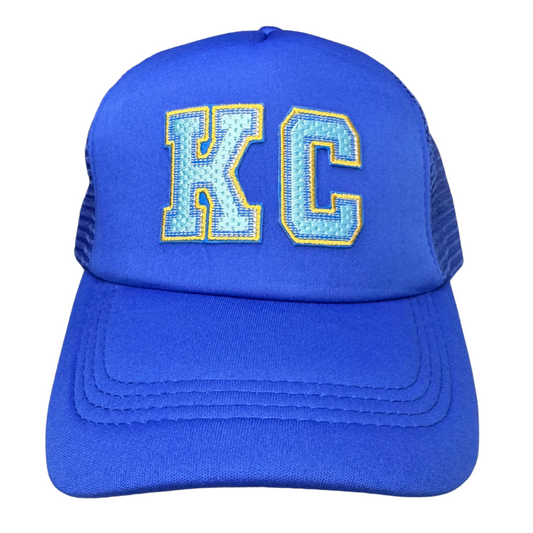 Front view of all royal blue trucker hat with light blue and gold embroidered KC patch
