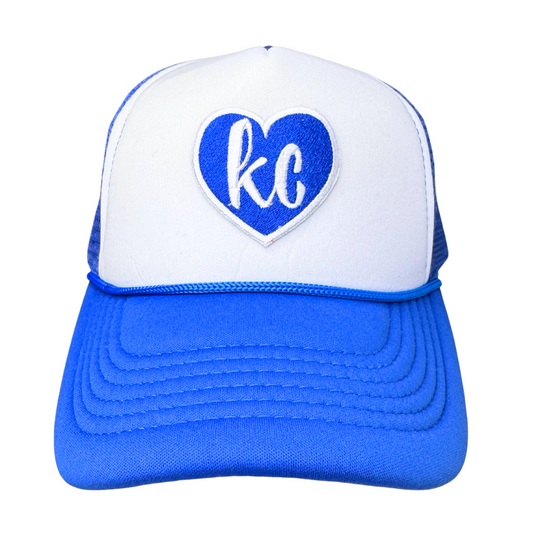 Front view of royal blue and white trucker hat with heart-shaped KC patch
