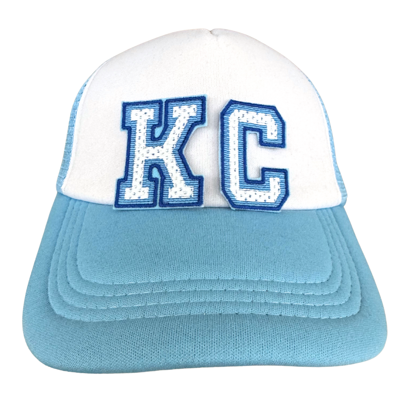 Trucker hat with KC varsity patch in white chenille and blue outline, styled for game day

