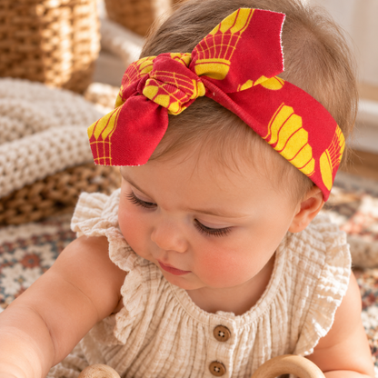 Baby wearing KC shuttlecock red and gold organic cotton tie headband