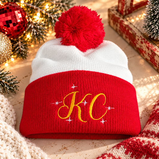 Red and white KC pom-pom beanie with gold KC embroidery and white sparkle accents in a festive setting