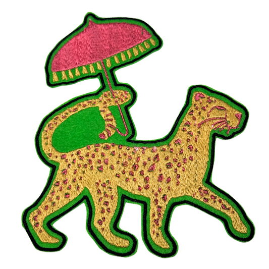 Embroidered patch of a yellow leopard with pink spots walking under a pink umbrella
