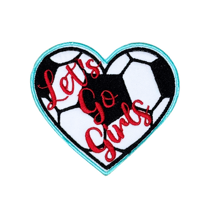 Hero shot of heart-shaped “Let’s Go Girls” soccer patch on white background

