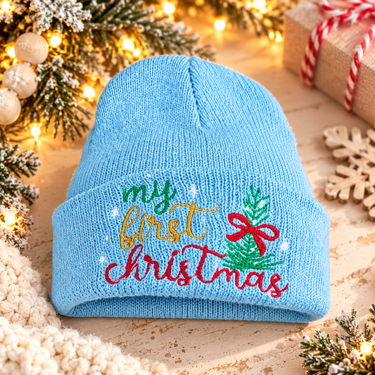 Light blue My First Christmas baby beanie with colorful embroidery in a warm holiday setting