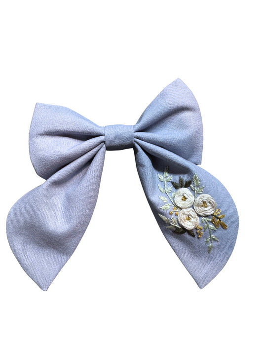 Light blue bow with floral embroidery on a white background
