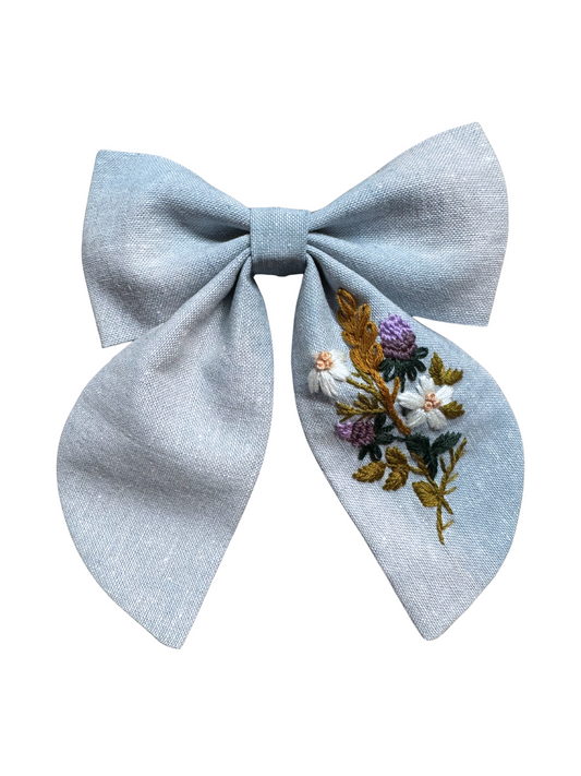 Light blue bow with floral embroidery on a white background